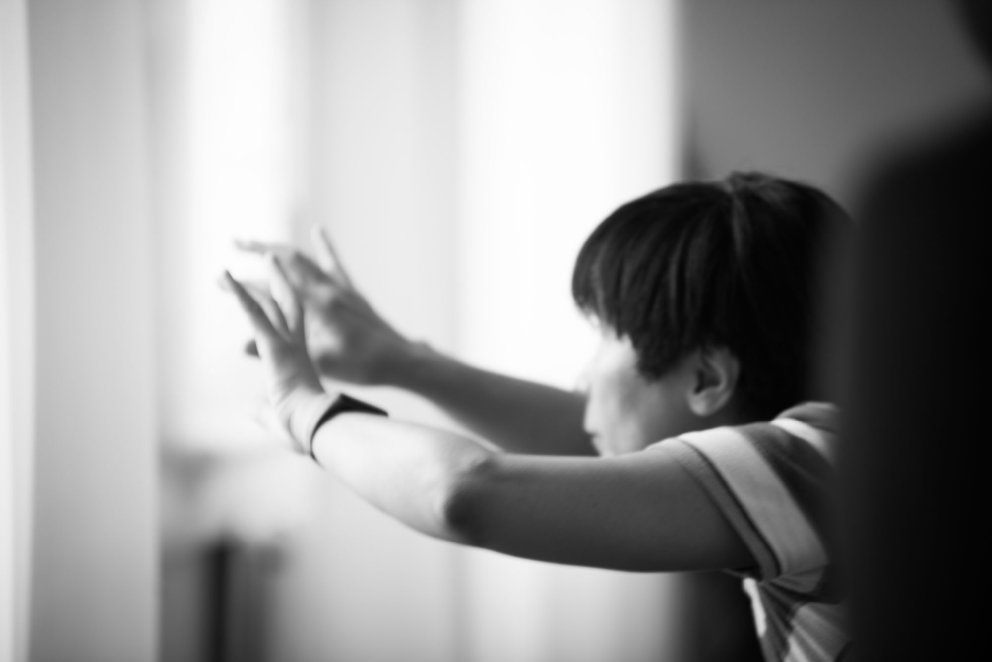 Hands reaching toward window light, black and white