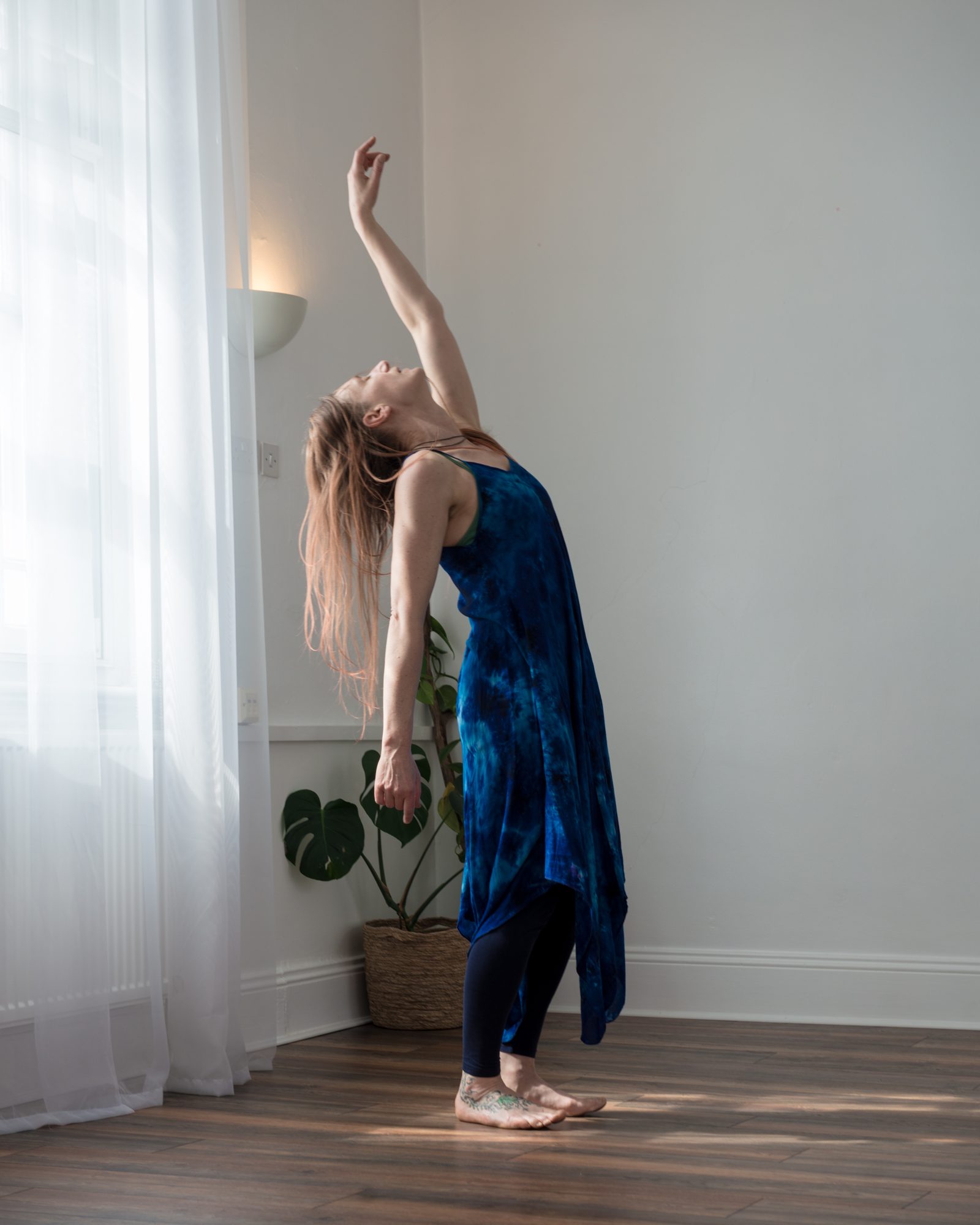 Rachel arching back in a graceful reach toward the window light